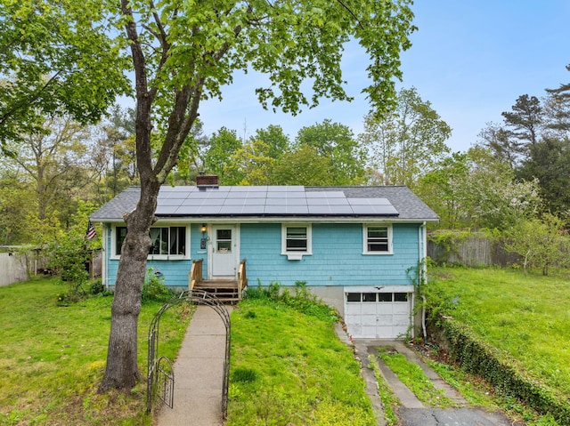 single story home with driveway, a chimney, roof mounted solar panels, and a garage