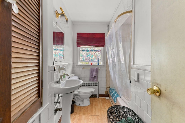 bathroom featuring radiator heating unit, tile walls, toilet, wood finished floors, and a shower with shower curtain