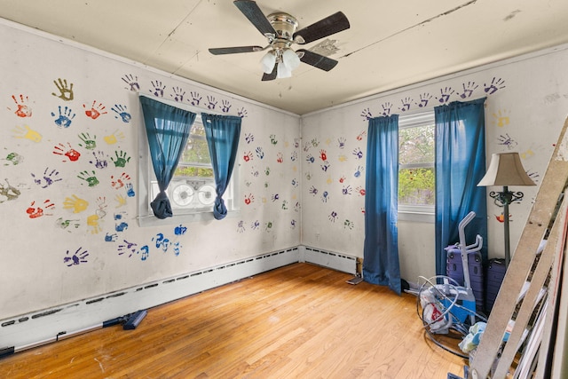 unfurnished bedroom with a baseboard heating unit, wood finished floors, and ceiling fan