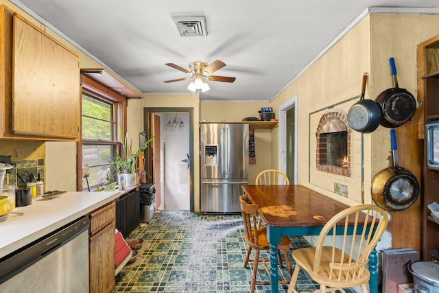 kitchen featuring appliances with stainless steel finishes, a ceiling fan, light countertops, crown molding, and dark flooring