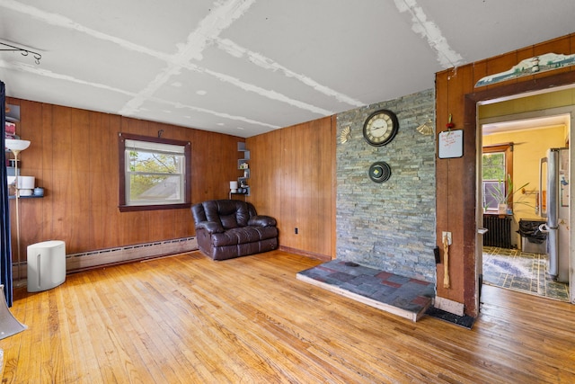 sitting room featuring baseboard heating, plenty of natural light, hardwood / wood-style flooring, and wooden walls