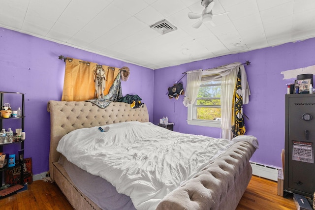 bedroom featuring wood finished floors and baseboard heating