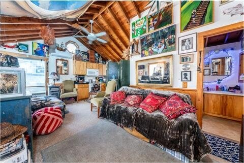 living room featuring vaulted ceiling, ceiling fan, and wood walls