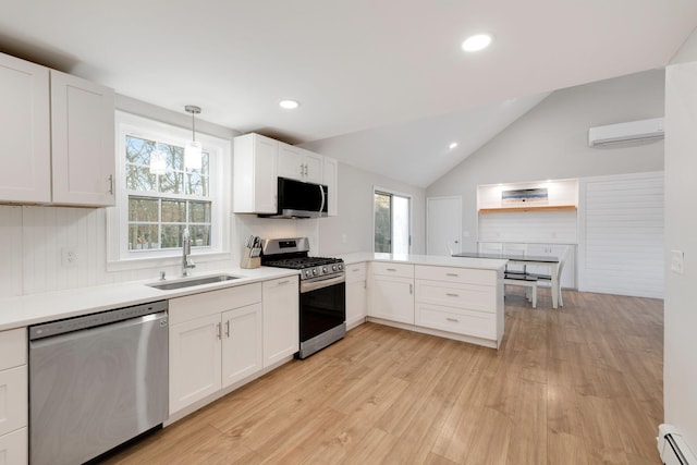 kitchen featuring a wall mounted AC, a sink, appliances with stainless steel finishes, a peninsula, and baseboard heating