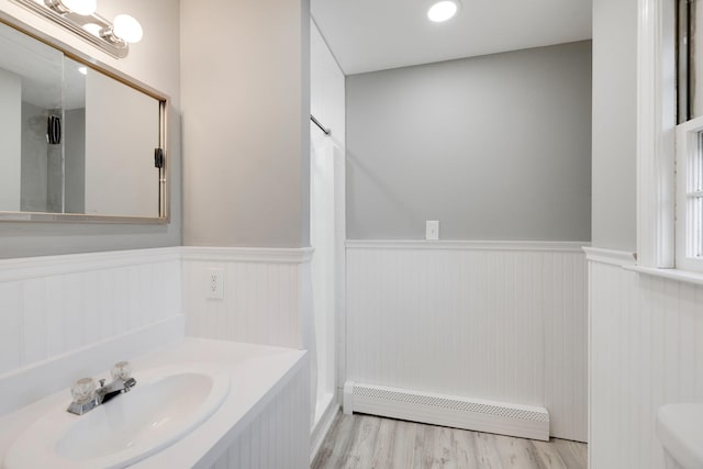 full bathroom featuring a baseboard heating unit, wood finished floors, a shower with shower curtain, wainscoting, and vanity