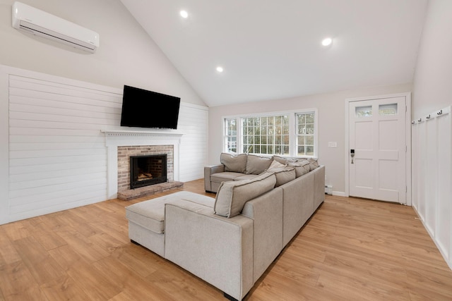 living area featuring light wood finished floors, a fireplace, high vaulted ceiling, and a wall mounted AC