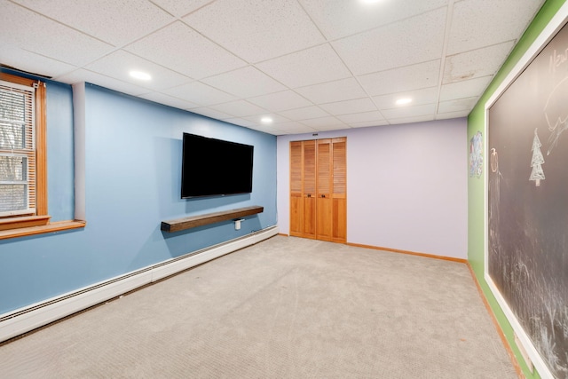 basement with a baseboard heating unit, carpet flooring, baseboards, and a drop ceiling