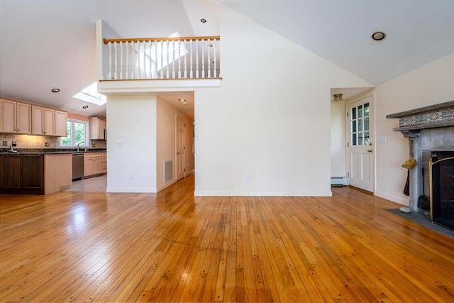 40 Thacher Shore Rd, Yarmouth Port, MA 02675 - unfurnished living room with high vaulted ceiling, light wood-type flooring, a baseboard radiator, baseboards, and a sink
