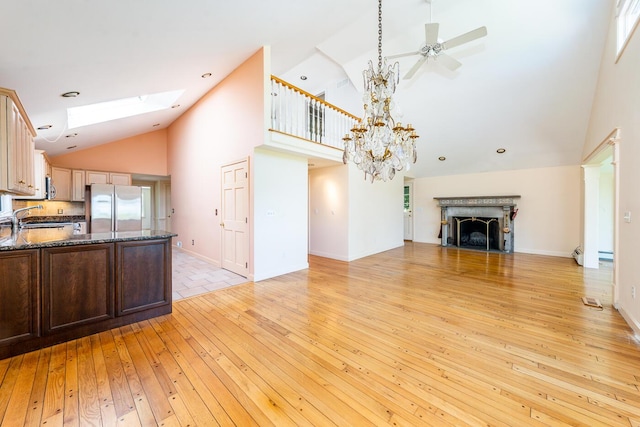 40 Thacher Shore Rd, Yarmouth Port, MA 02675 - unfurnished living room with high vaulted ceiling, light wood-style floors, a fireplace, a ceiling fan, and a sink