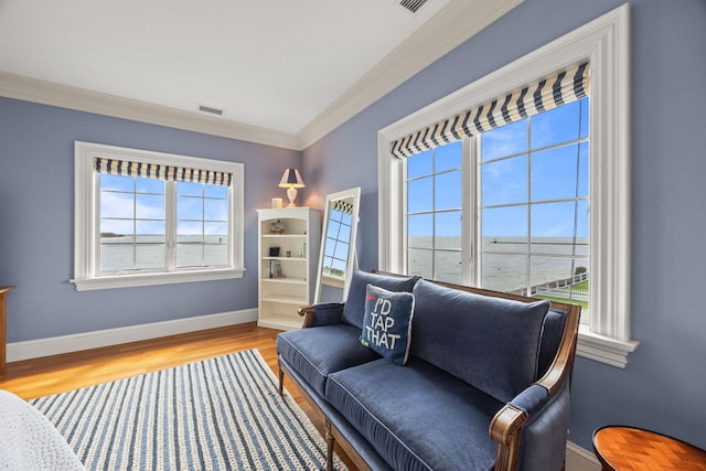 living area with plenty of natural light, crown molding, wood finished floors, and baseboards