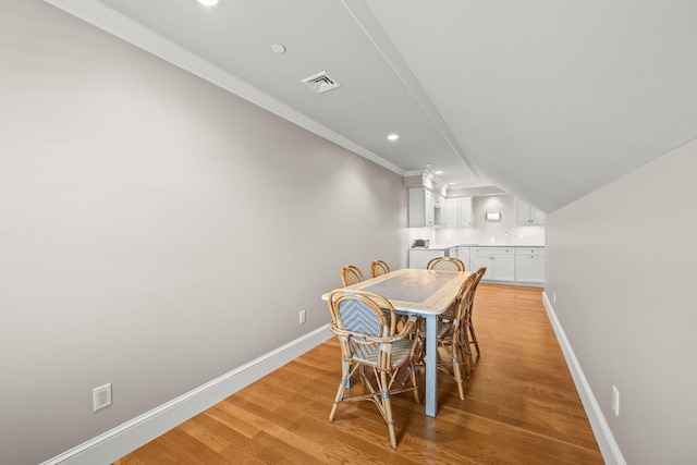dining space featuring baseboards, ornamental molding, light wood finished floors, and recessed lighting