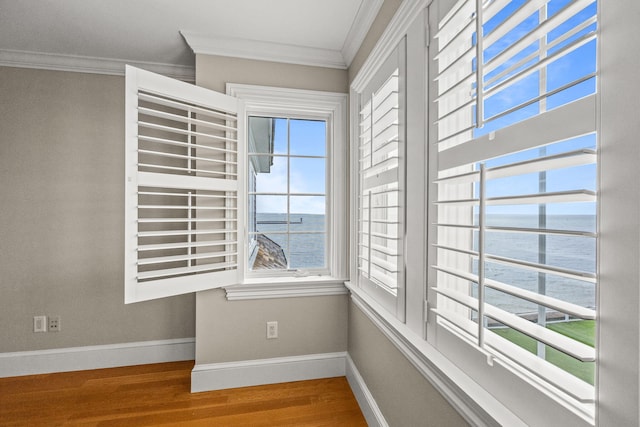 spare room with crown molding, wood finished floors, baseboards, and a water view