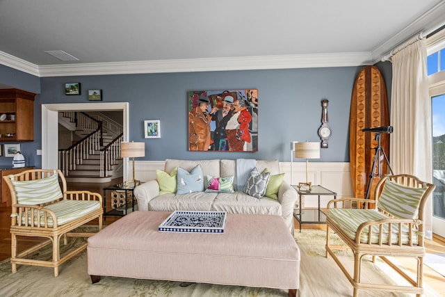living area featuring ornamental molding, wainscoting, and stairway