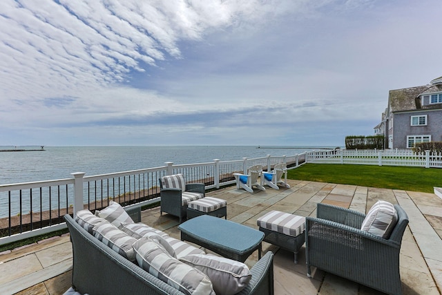 view of patio with an outdoor living space, a water view, and fence