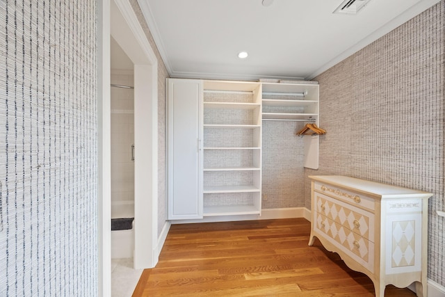 walk in closet with light wood finished floors