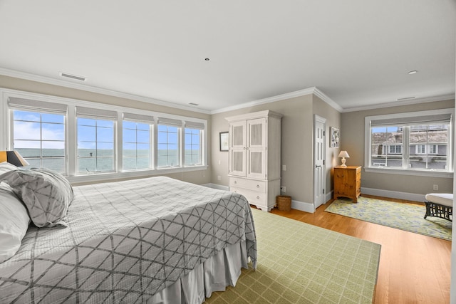bedroom with baseboards, wood finished floors, and ornamental molding
