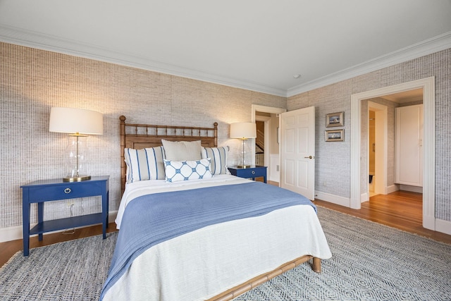 bedroom featuring wood finished floors, baseboards, ornamental molding, and wallpapered walls
