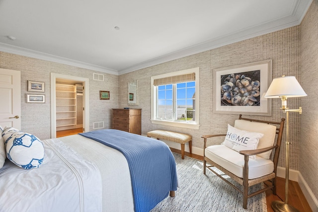 bedroom featuring ornamental molding, wood finished floors, baseboards, and wallpapered walls