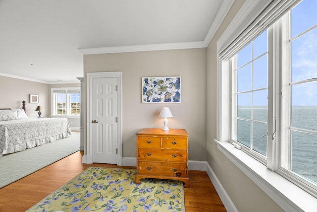 bedroom featuring wood finished floors, ornamental molding, access to exterior, baseboards, and a water view
