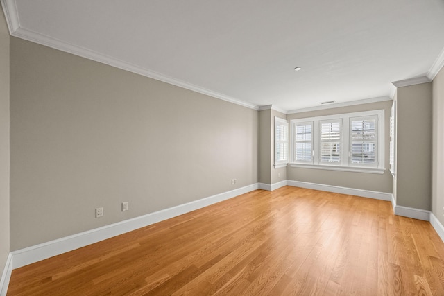 spare room featuring light wood-style floors, baseboards, and crown molding