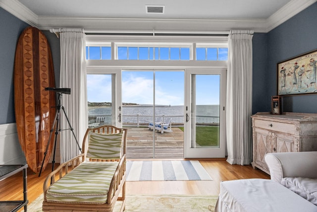 sitting room with wood finished floors, ornamental molding, and a water view