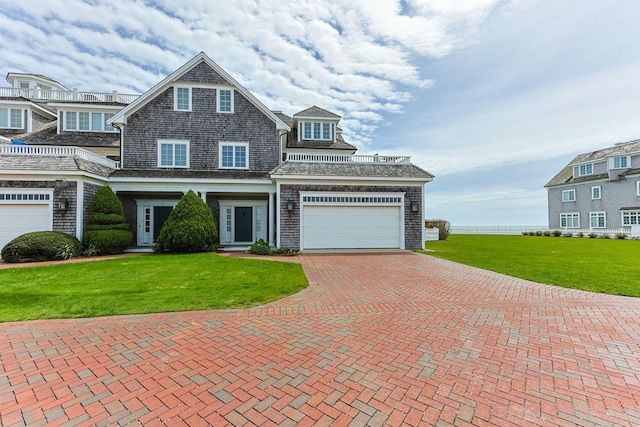 shingle-style home featuring decorative driveway, a front lawn, and a garage