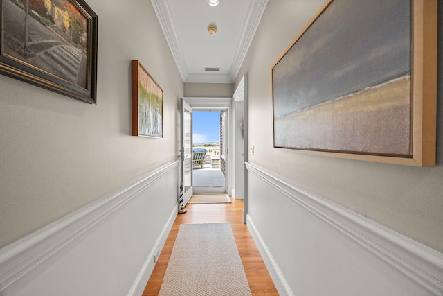 corridor featuring ornamental molding, light wood-type flooring, and baseboards