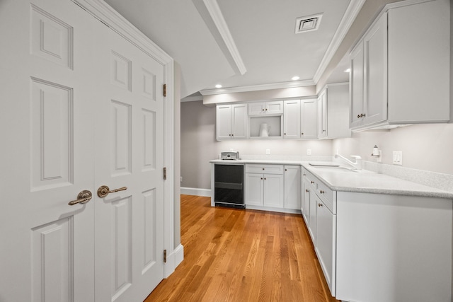 kitchen with ornamental molding, open shelves, white cabinetry, a sink, and light wood-style flooring