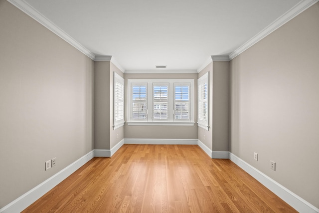 spare room featuring light wood finished floors, baseboards, and ornamental molding