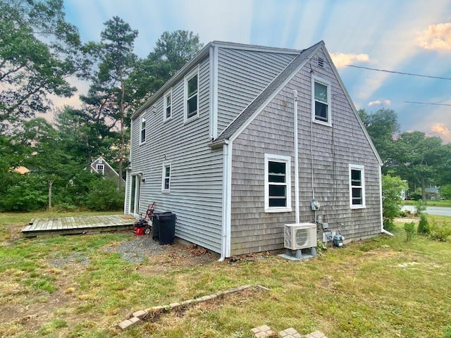 view of side of property with ac unit, a wooden deck, and a yard