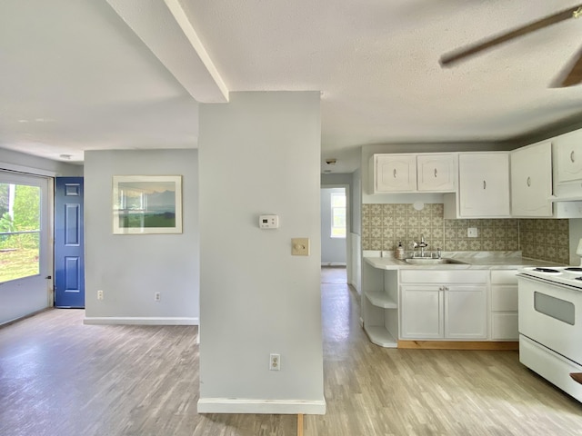 kitchen featuring decorative backsplash, plenty of natural light, white cabinets, and white electric range