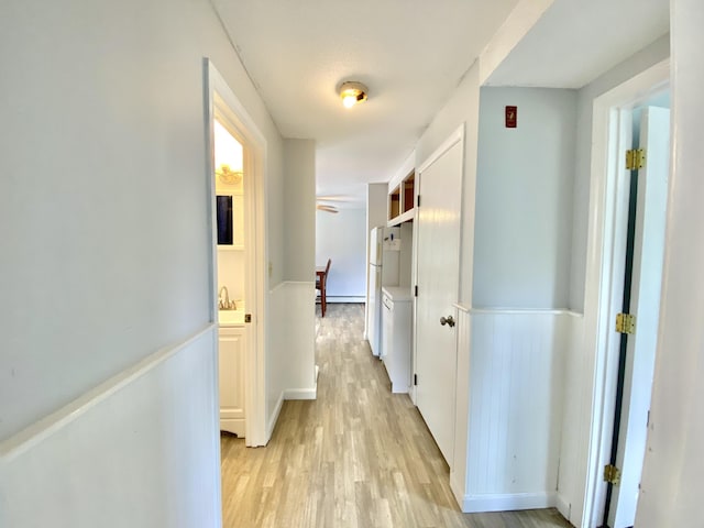 hallway featuring light wood-type flooring and a baseboard heating unit