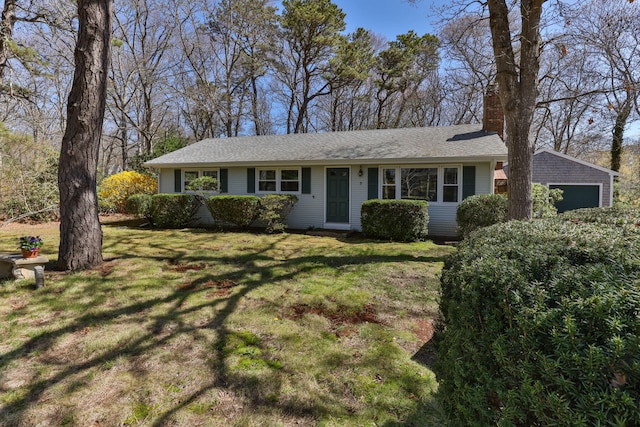 ranch-style home with roof with shingles, an attached garage, a chimney, and a front yard