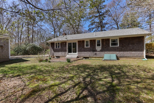 back of house with entry steps, a chimney, a yard, and a shingled roof