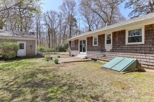 back of property with a shingled roof, a yard, and entry steps