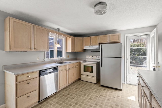 kitchen featuring light brown cabinetry, light countertops, under cabinet range hood, a sink, and stainless steel appliances