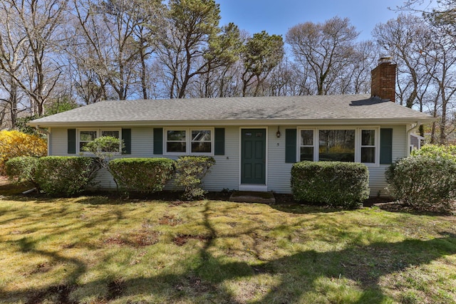 ranch-style home featuring roof with shingles, a chimney, and a front yard