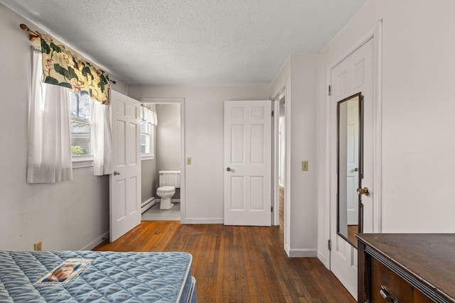 bedroom featuring baseboards, a textured ceiling, baseboard heating, and dark wood-type flooring