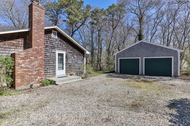 view of home's exterior with a detached garage, an outdoor structure, and a chimney