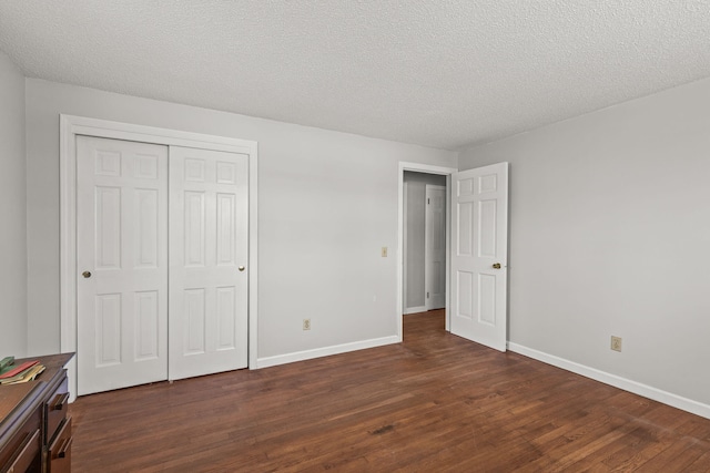 unfurnished bedroom featuring baseboards, a closet, dark wood finished floors, and a textured ceiling
