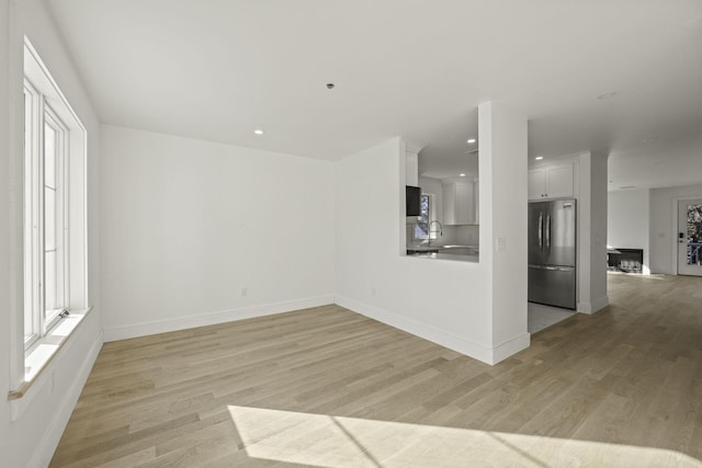 unfurnished living room featuring sink and light hardwood / wood-style floors