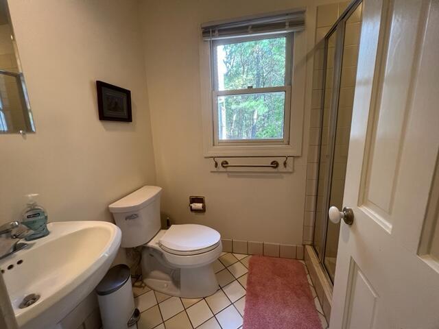 bathroom featuring sink, toilet, a shower with door, and tile patterned flooring