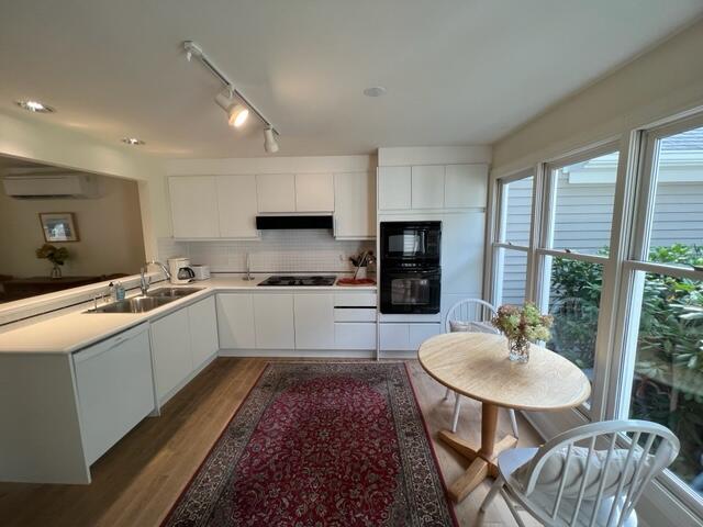 kitchen featuring sink, black appliances, white cabinetry, and an AC wall unit