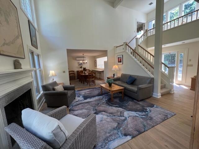 living room featuring wood-type flooring, an inviting chandelier, and a towering ceiling