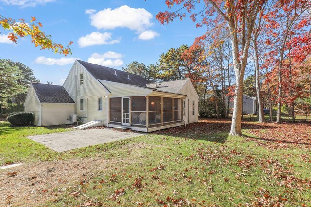 rear view of house featuring a patio area, a lawn, and a sunroom