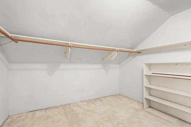 spacious closet with light carpet and vaulted ceiling