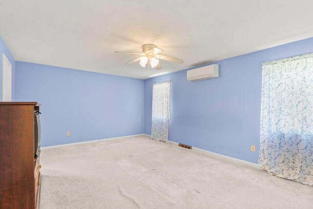 carpeted spare room featuring ceiling fan and a wall unit AC