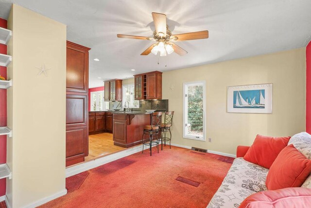 carpeted living room featuring sink and ceiling fan