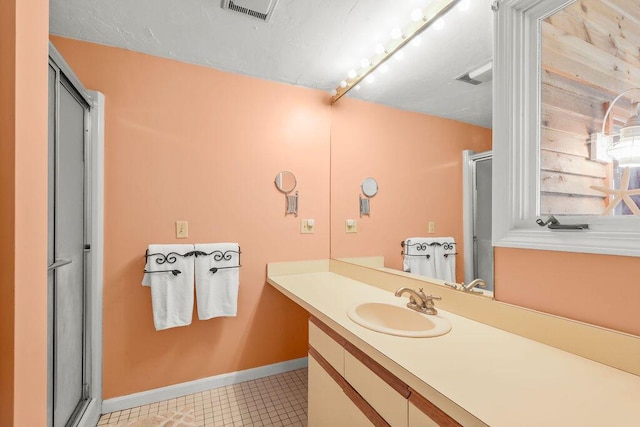 bathroom featuring a shower with shower door and vanity