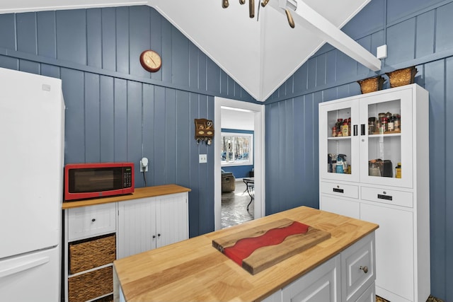 kitchen featuring wooden walls, wood counters, lofted ceiling, white cabinets, and white fridge